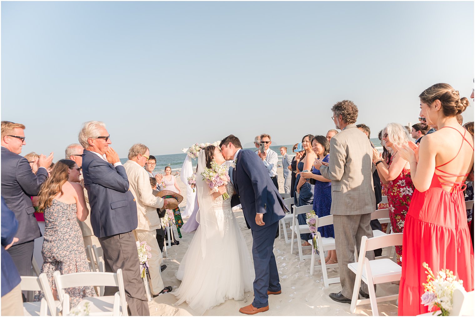 bride and groom kiss in aisle after beach wedding ceremony in Avalon NJ