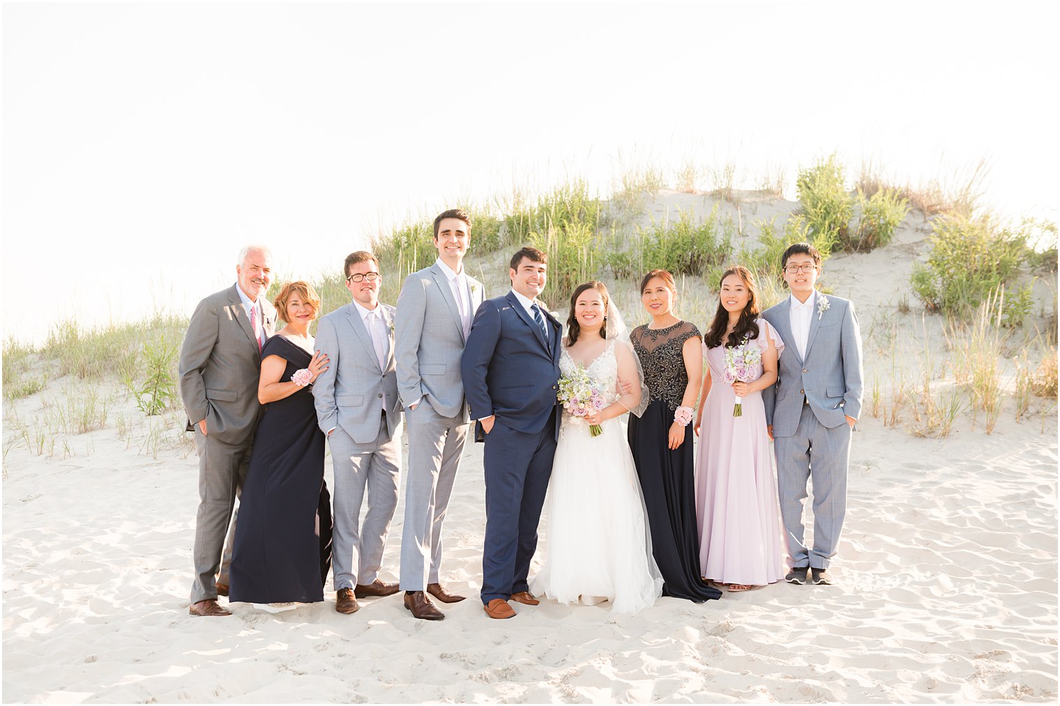 bride and groom stand with family after beach wedding ceremony