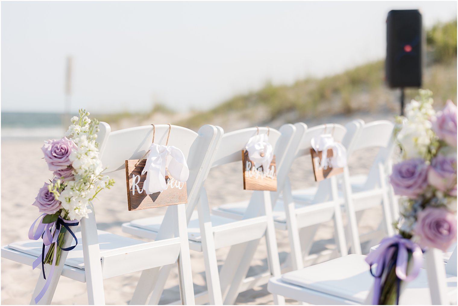 reserved signs hang on white chairs for beach wedding ceremony in Avalon NJ