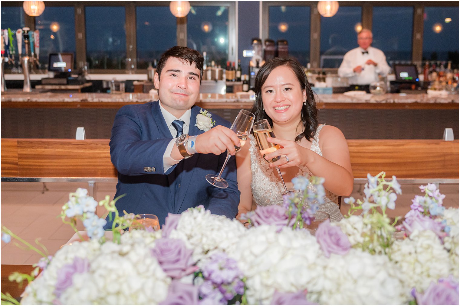 newlyweds toast champagne behind floral display at Icona Winddrift