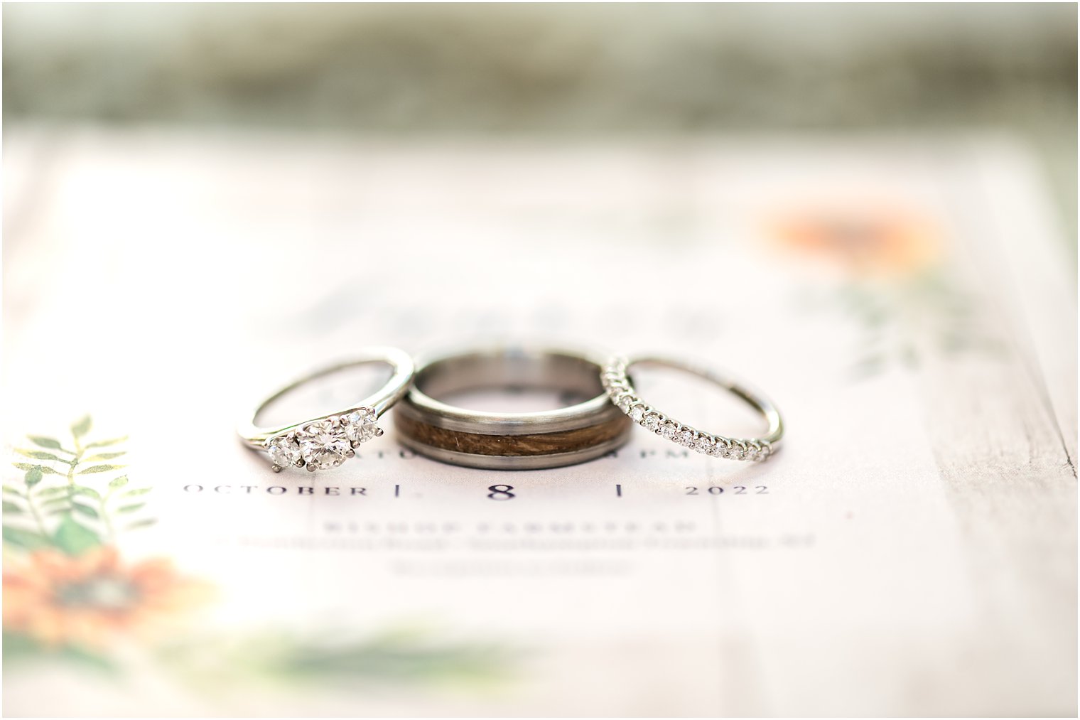 three wedding bands lean together on invitations for fall wedding