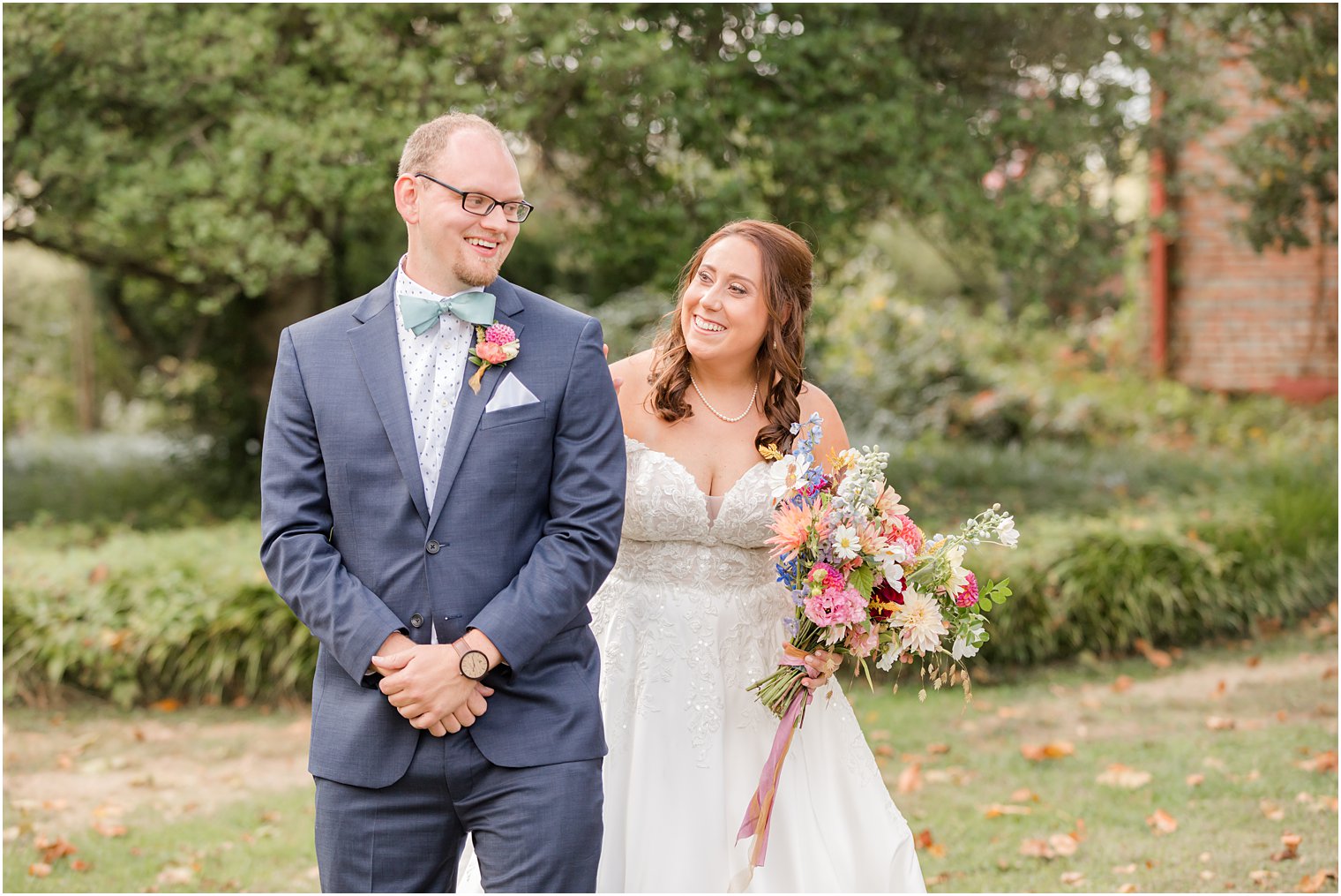 groom in navy suit turns to look at bride during first look at Bishop Hall Farmstead