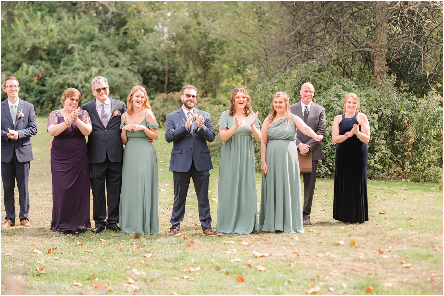family and bridal party cheers for couple during first look 