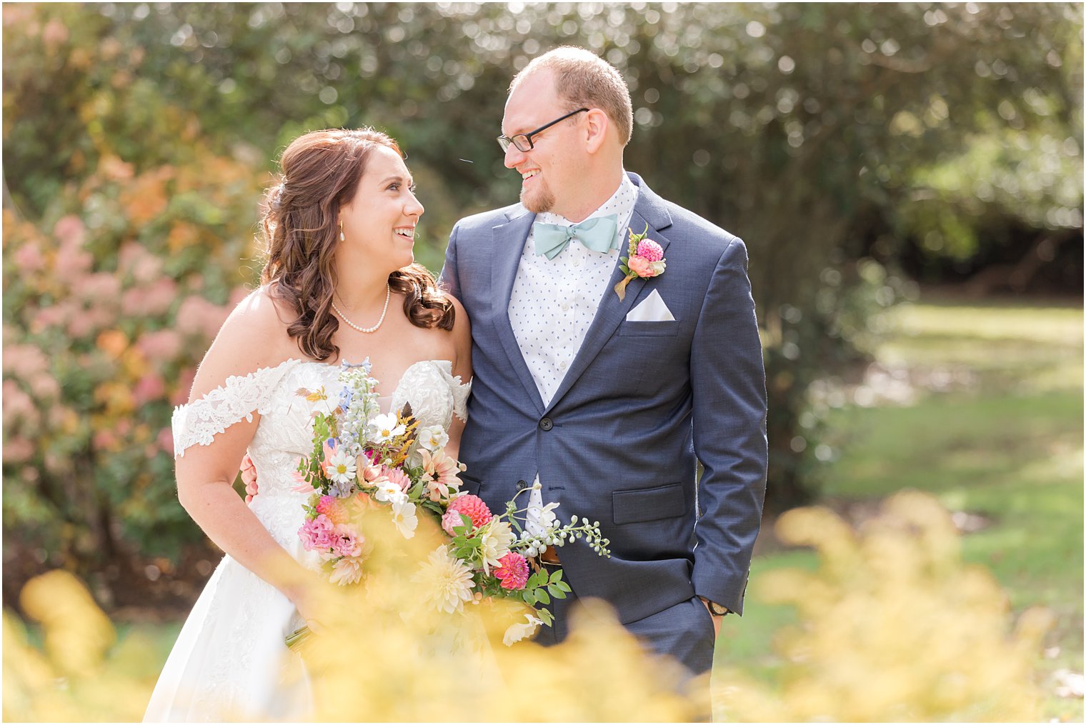 bride and groom smile at each other during wedding portraits in garden