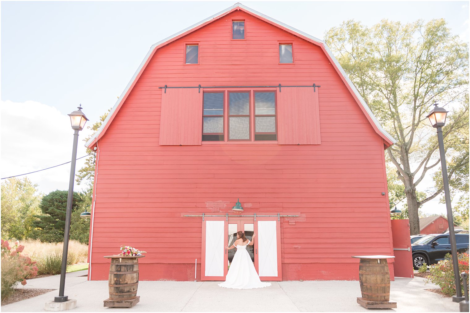 bride poses in front of red barn at Bishop Hall Farmstead