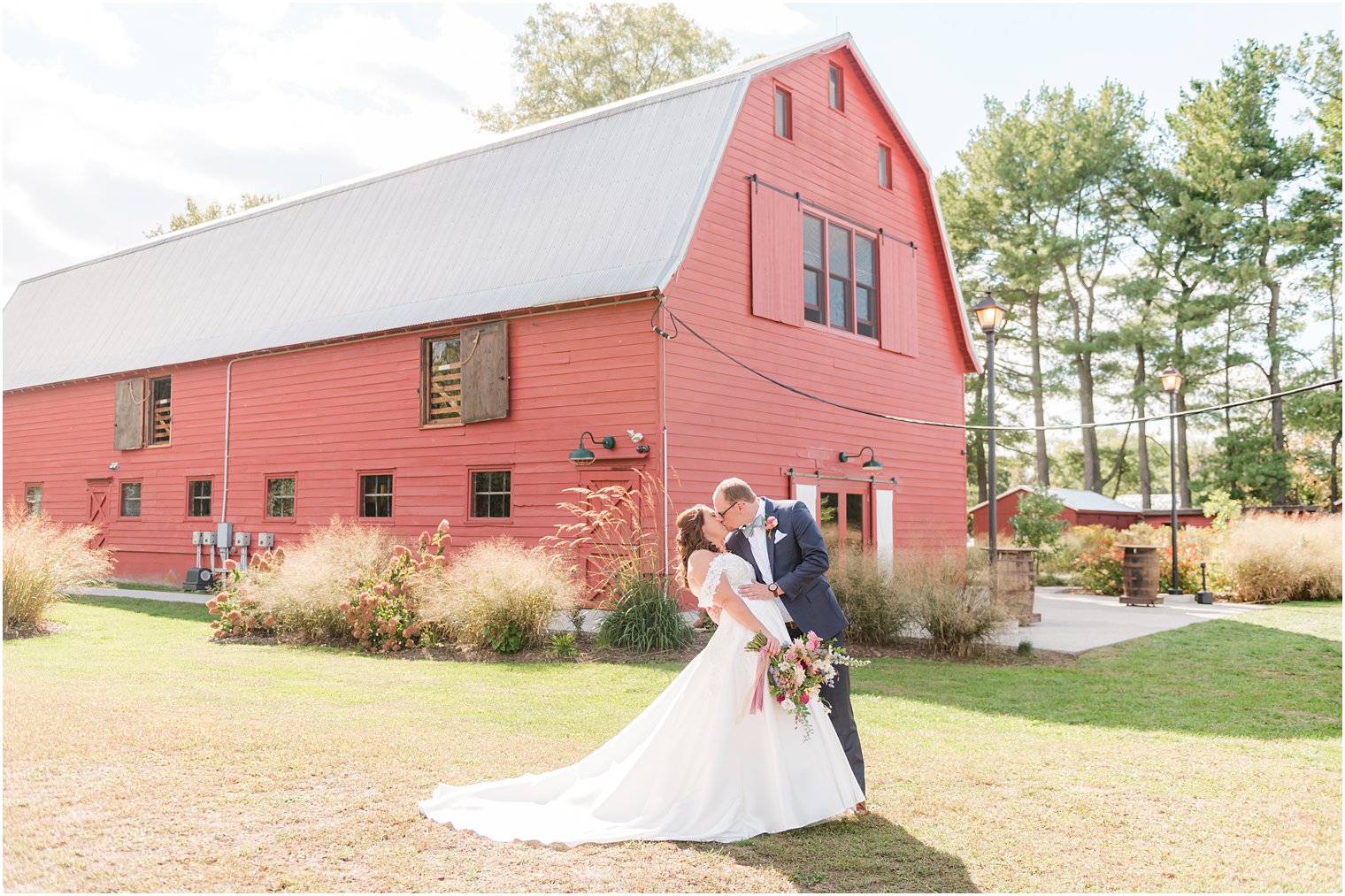 bride and groom kiss outside of the red barn at Bishop Hall Farmstead