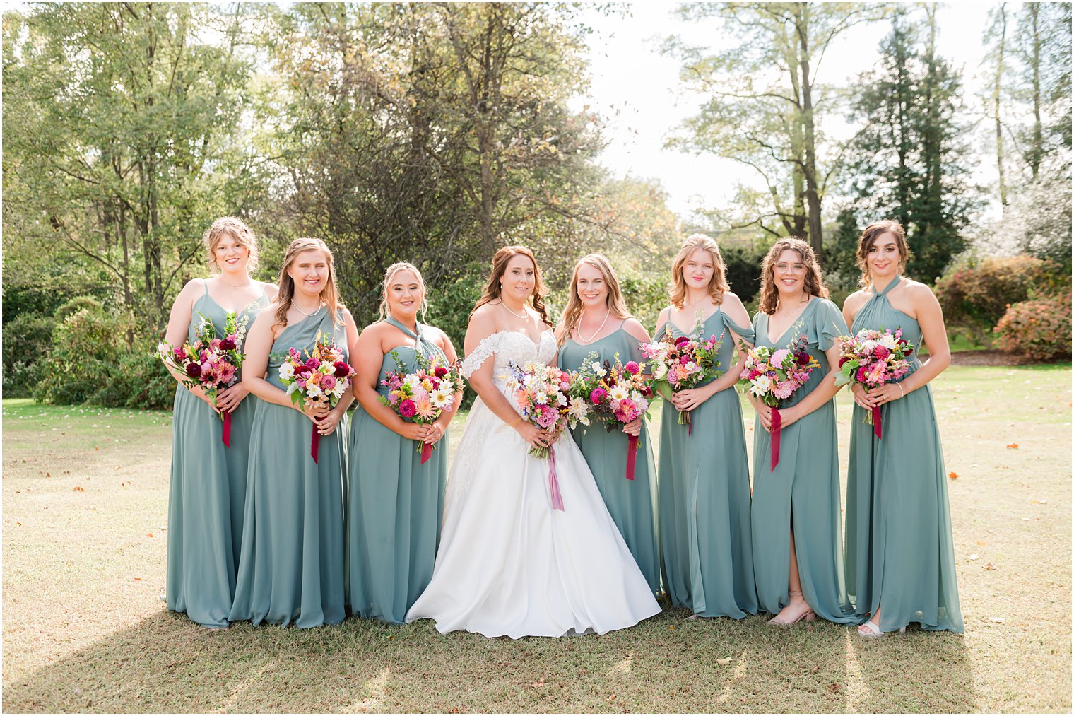 bride poses with bridesmaids in sea glass green gowns
