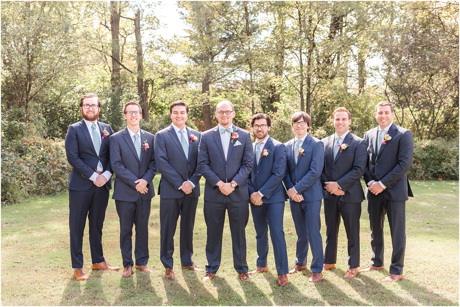 groom stands with groomsmen in navy blue suits