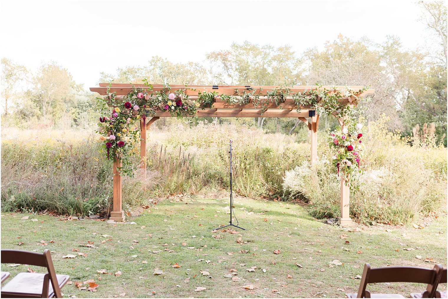 wooden arbor with wildflowers for fall wedding ceremony outdoors on lawn at Bishop Hall Farmstead
