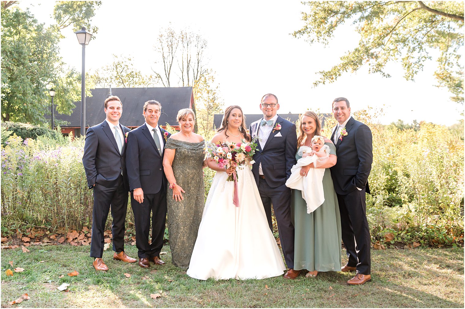 bride and groom pose with family on lawn