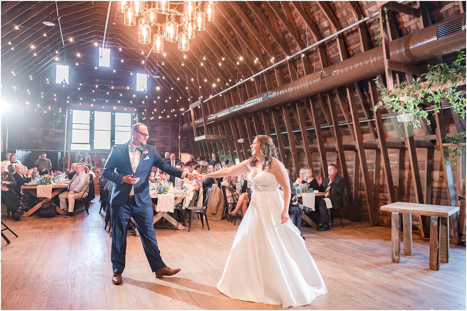 groom twirls bride in barn during reception 