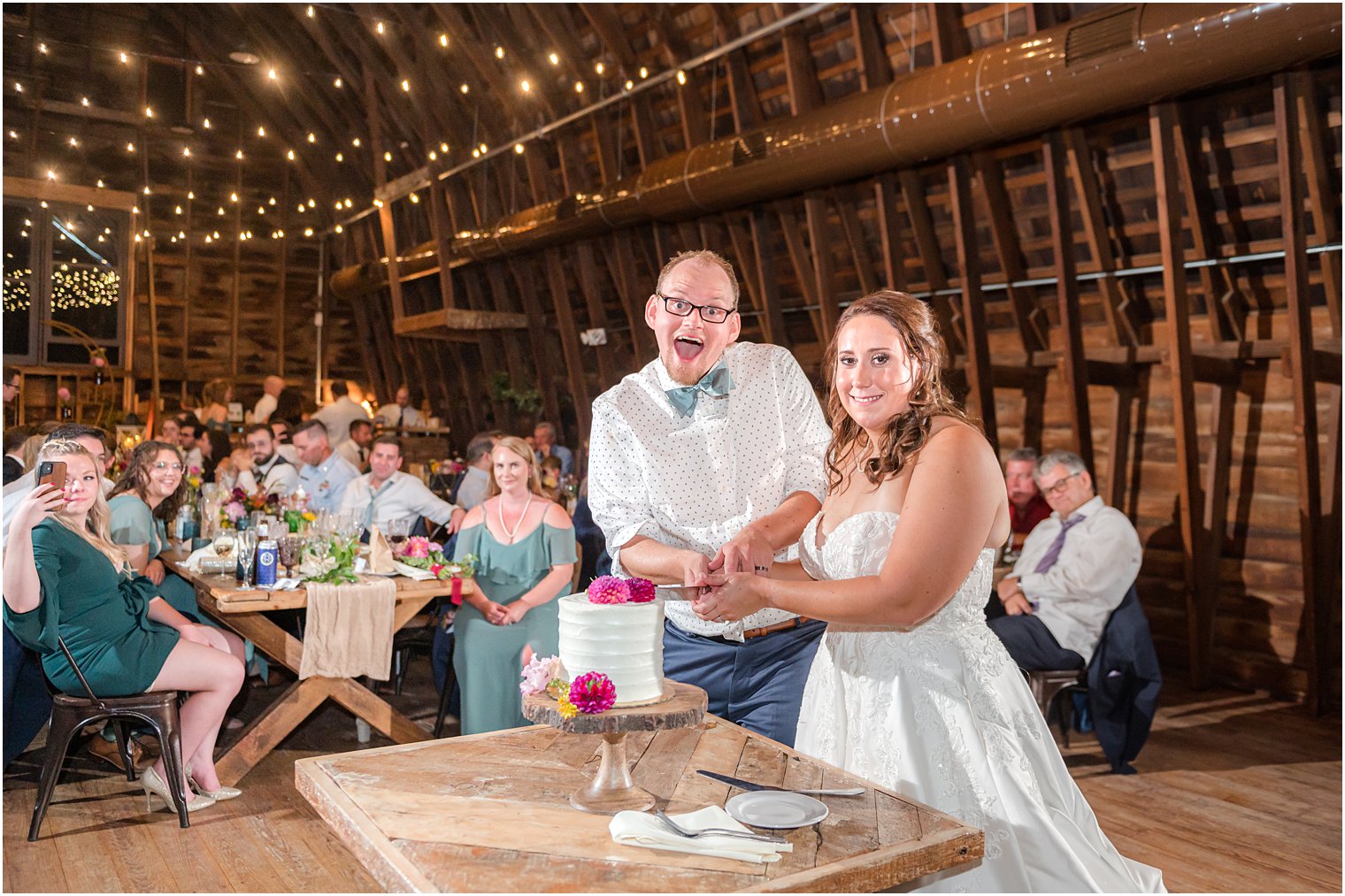 newlyweds cut wedding cake smiling together at Bishop Hall Farmstead