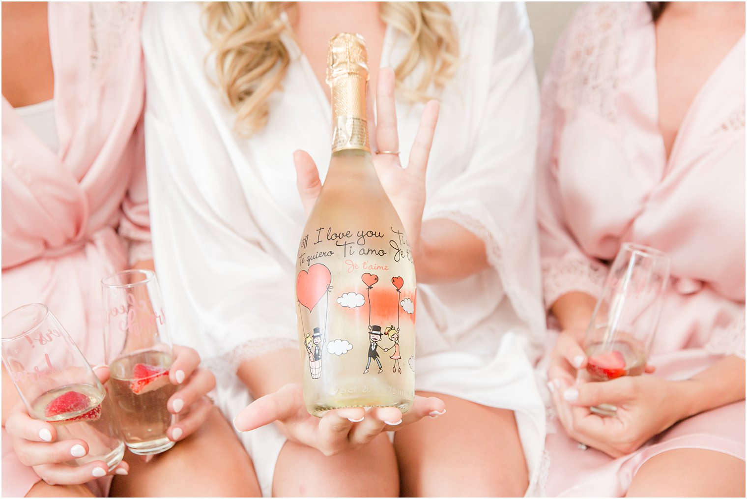 bride in pink robe holds champagne bottle with custom drawing 