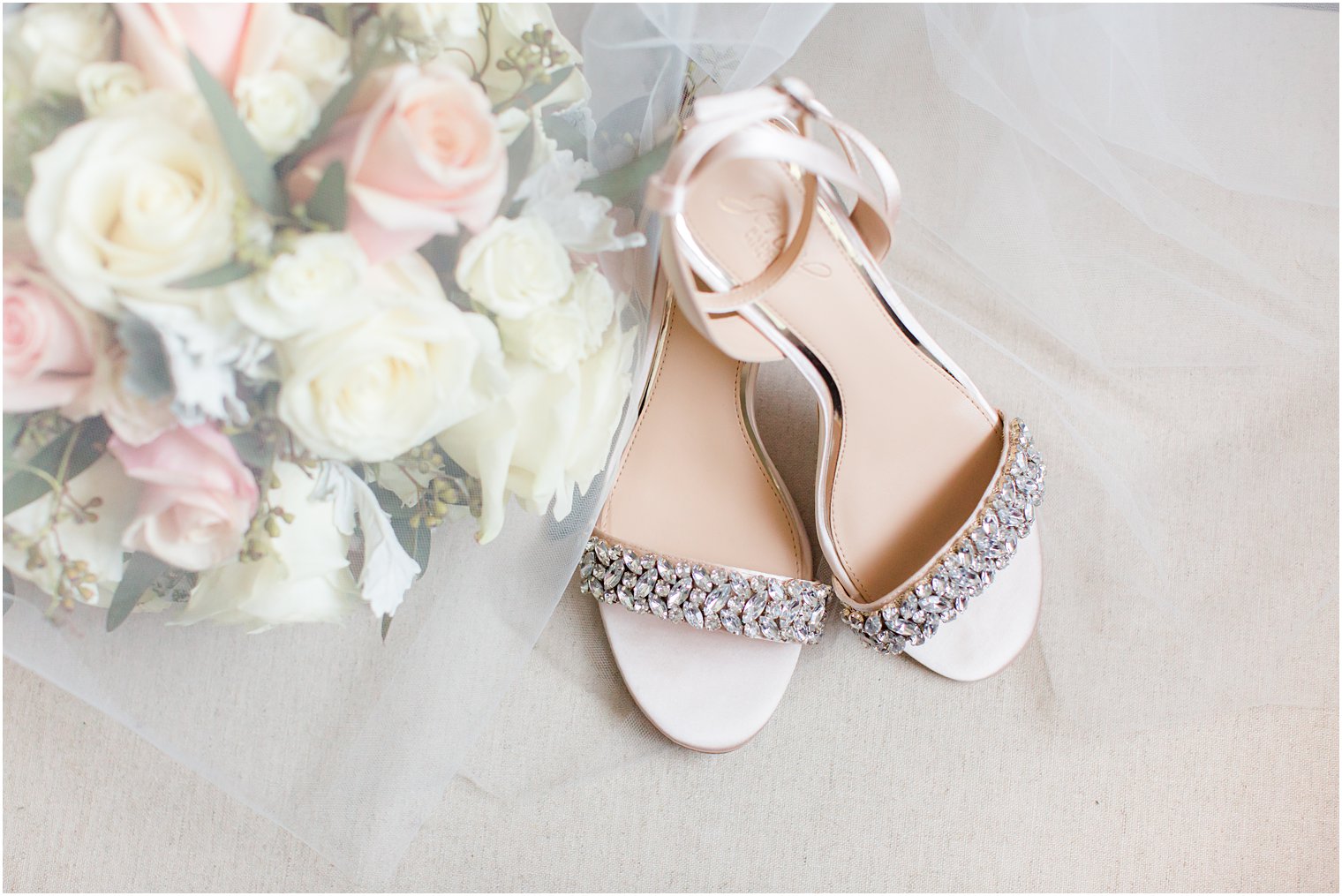 bride's shoes rest by pastel pink and ivory bouquet of roses 