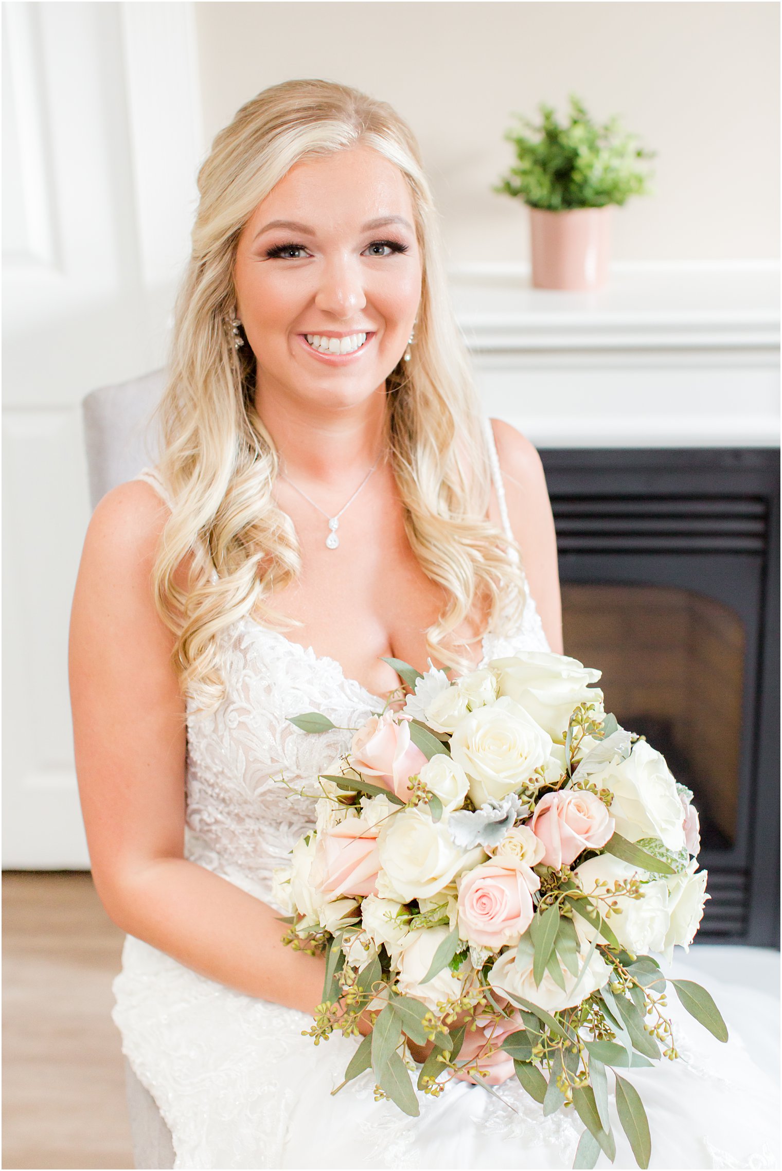 bride sits in v-neck wedding gown with bouquet of white and pink flowers 