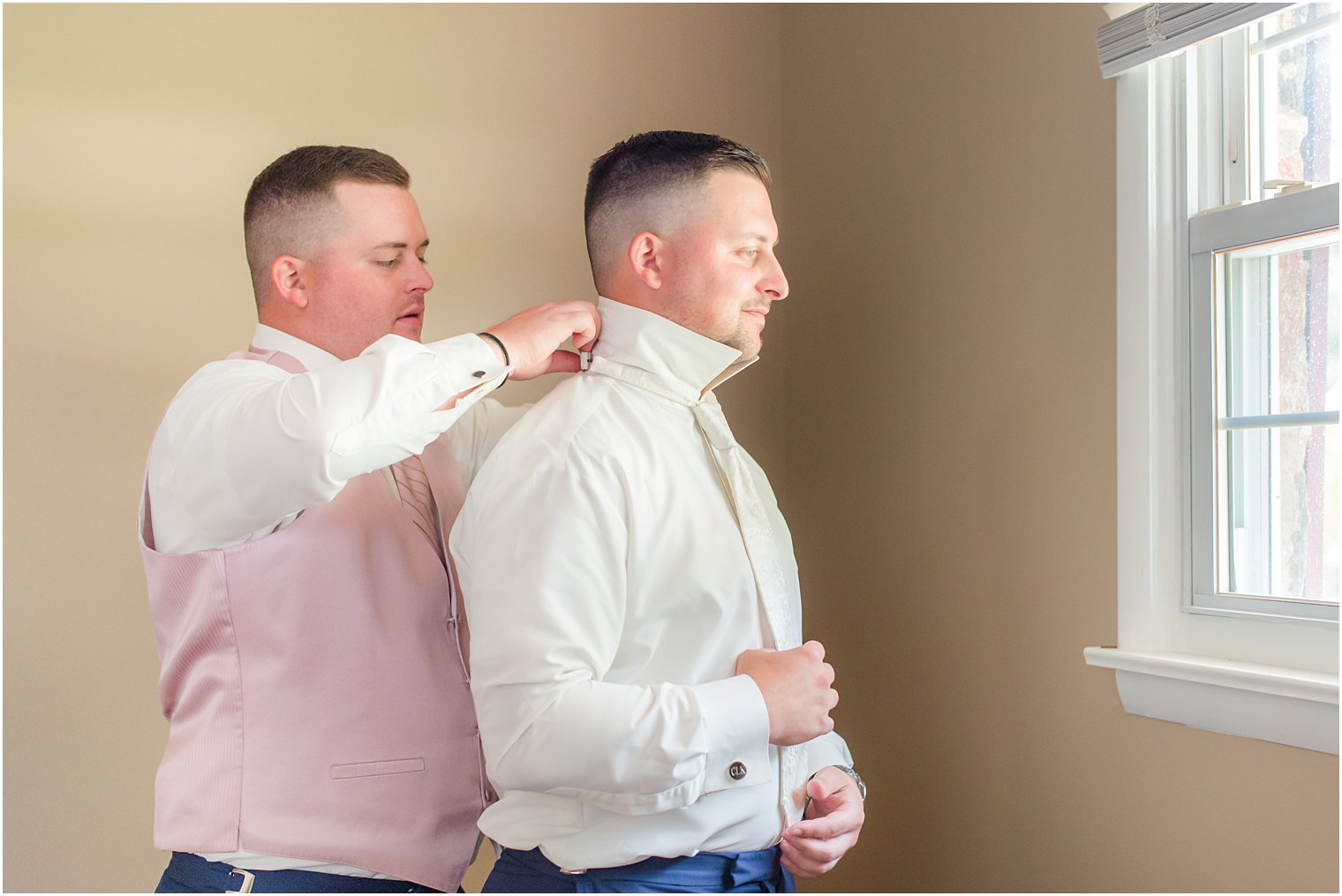 groomsman helps groom with bowtie before wedding day 