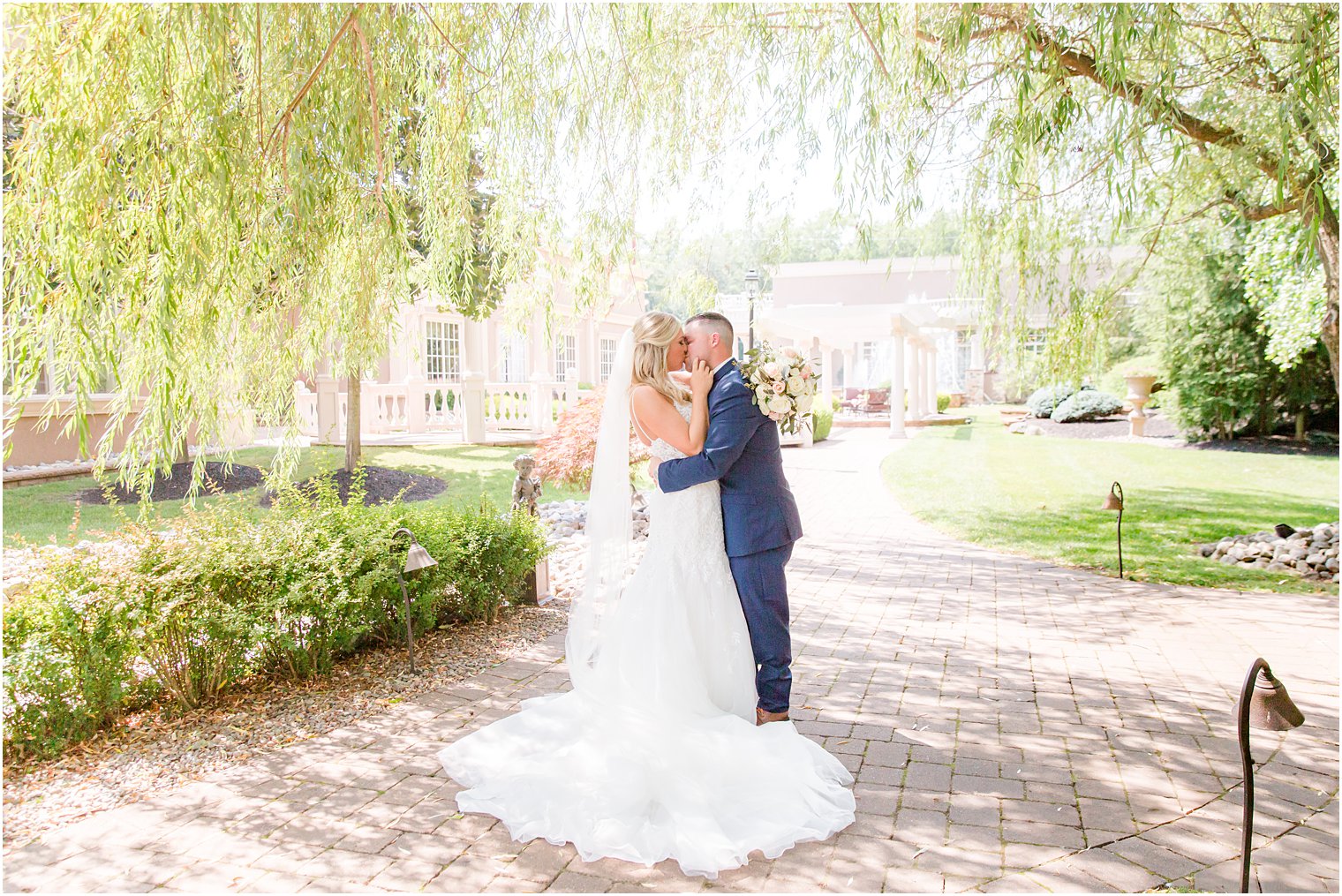 newlyweds kiss under willow tree at Brigalia's