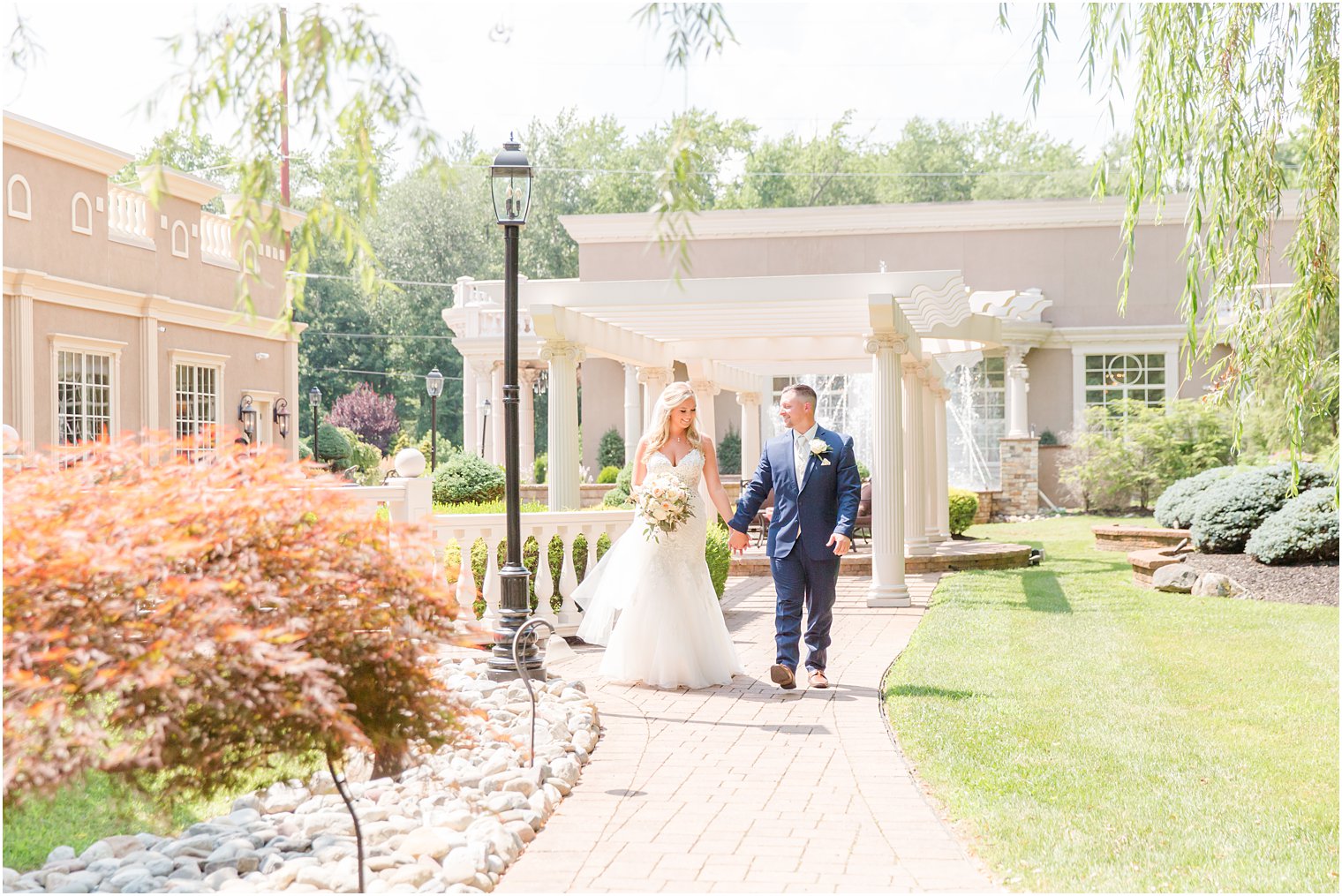 bride and groom hold hands walking down path at Brigalia's