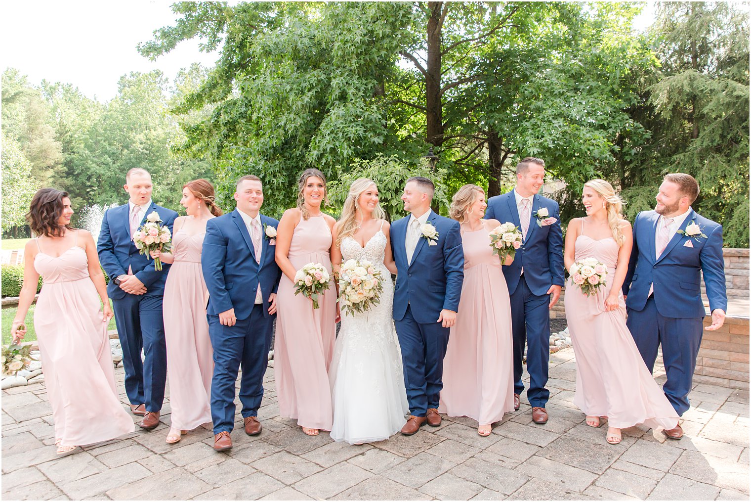 newlyweds stand with wedding party in pink and blue attire 