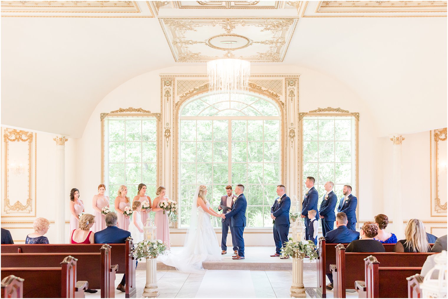 couple holds hands standing by windows during wedding ceremony in chapel at Brigalia's