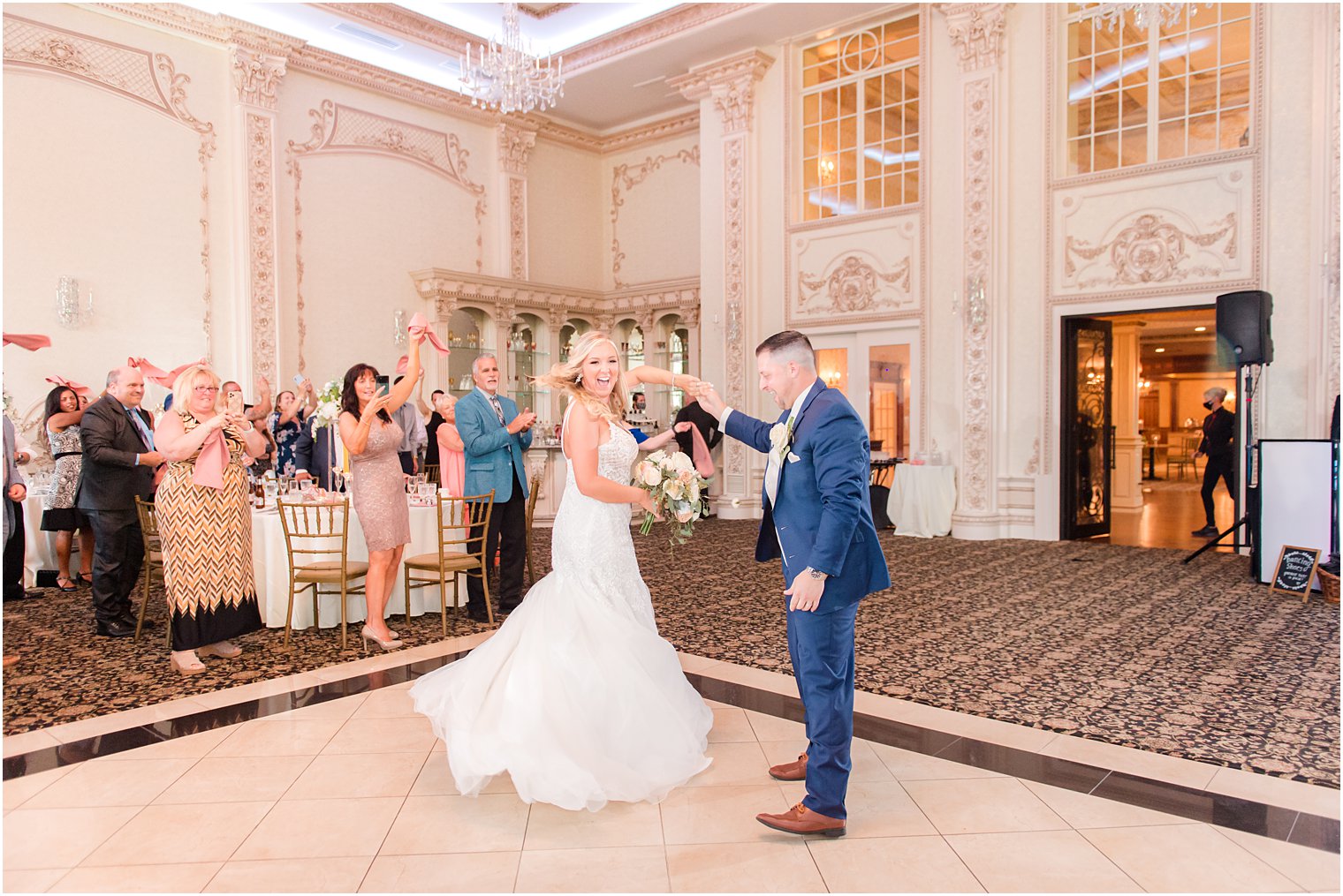 groom in navy suit twirls bride on dance floor at Brigalia's