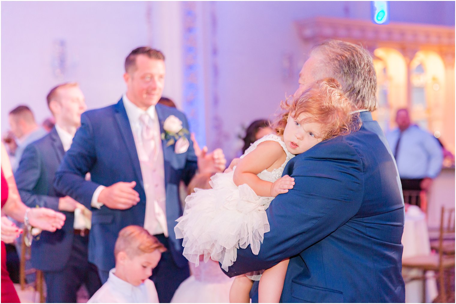 flower girl lays on grandfather's arm during wedding reception dancing 