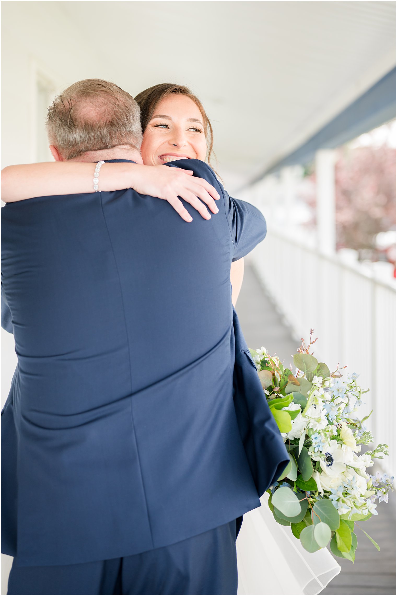 bride hugs dad during first look on balcony at Crystal Point Yacht Club