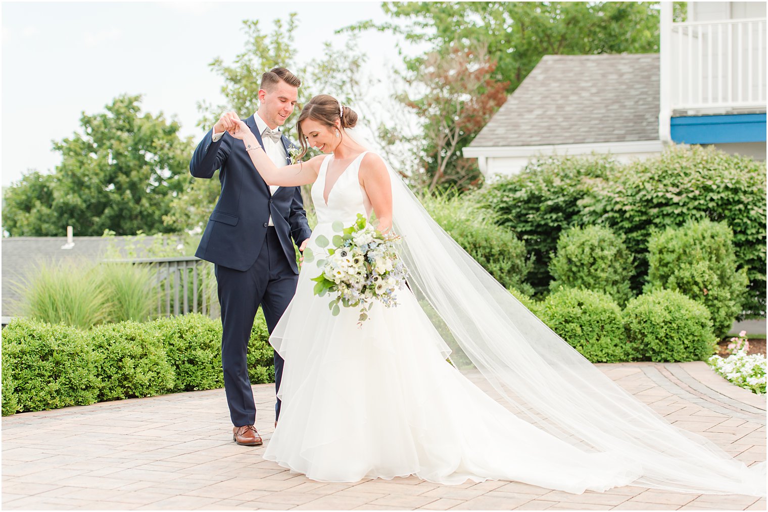groom helps bride twirl on patio at Crystal Point Yacht Club