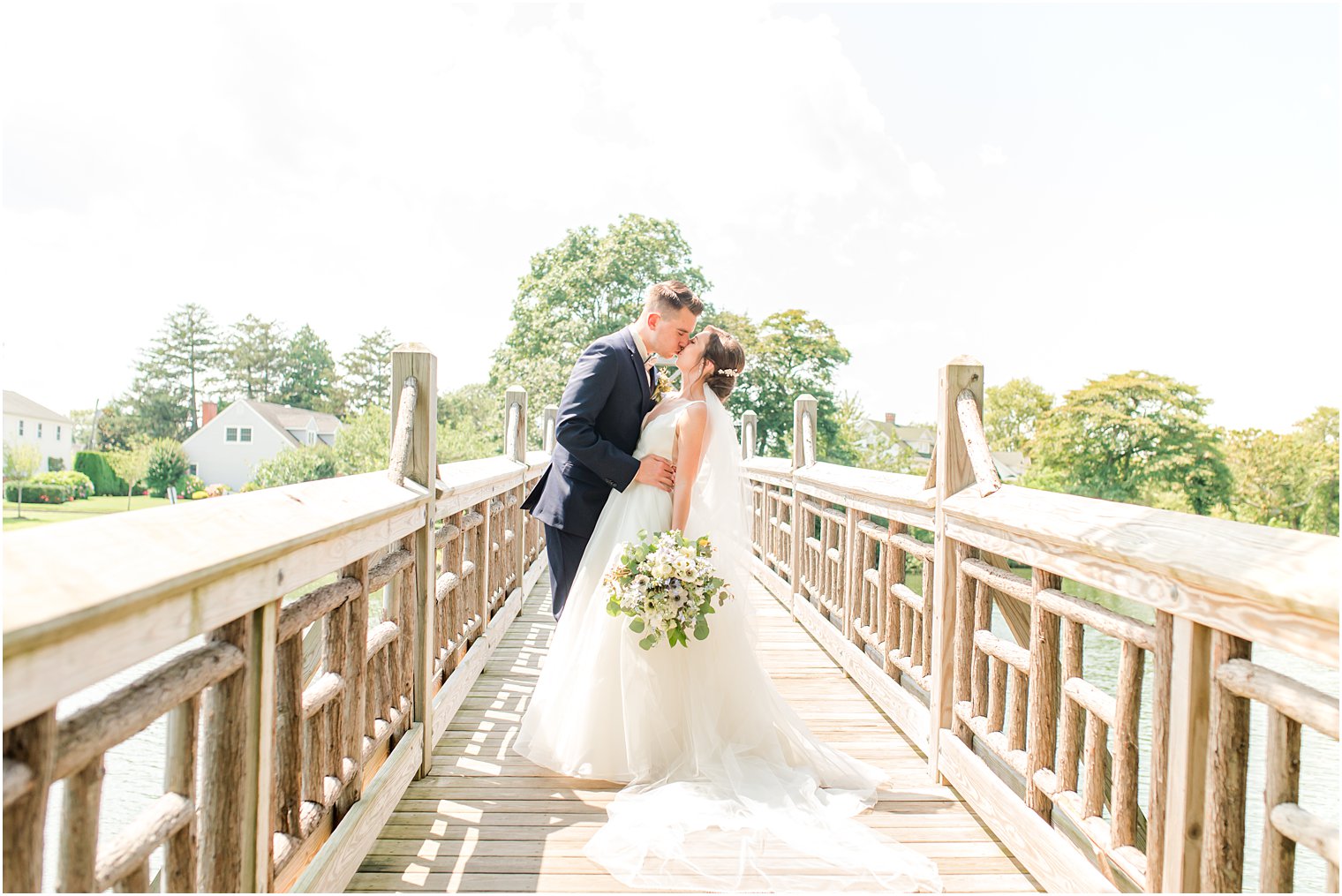 groom dips bride a little kissing her on wooden bridge at Spring Lake Park