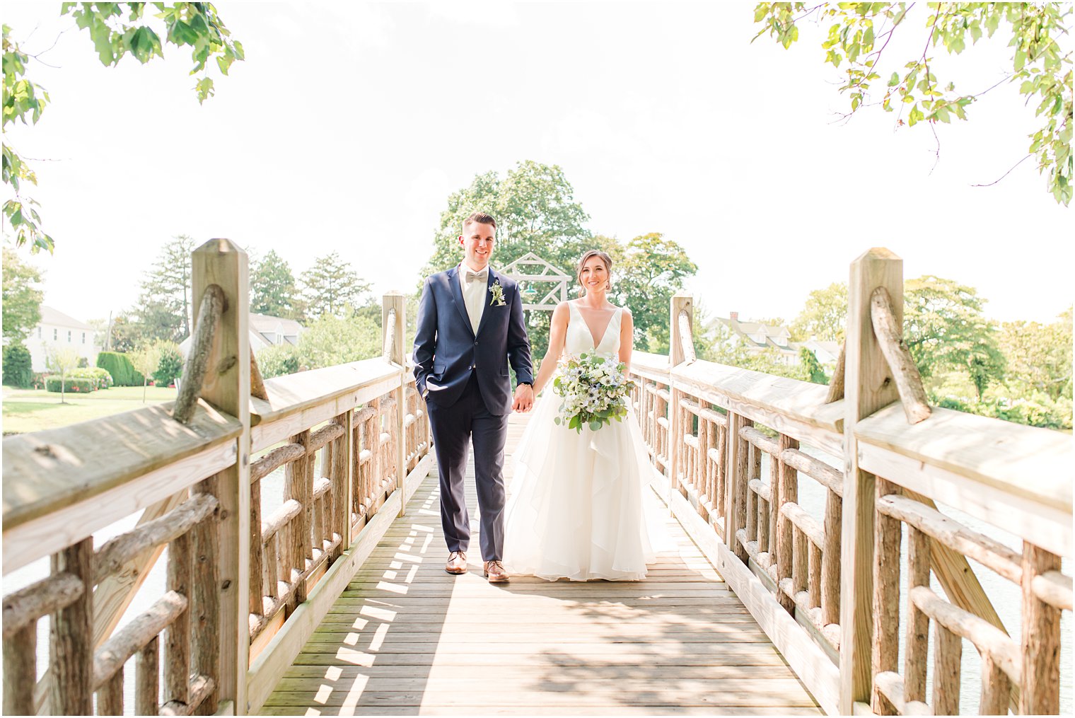 bride and groom hold hands walking on bridge in Spring Lake Park