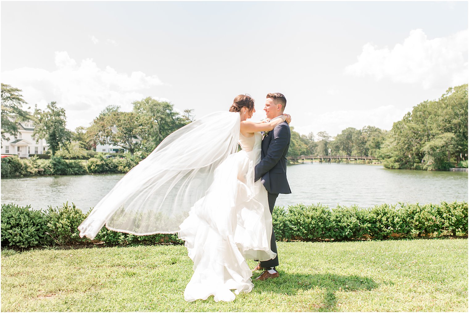 groom twirls bride in wedding gown by lake in Spring Lake Park