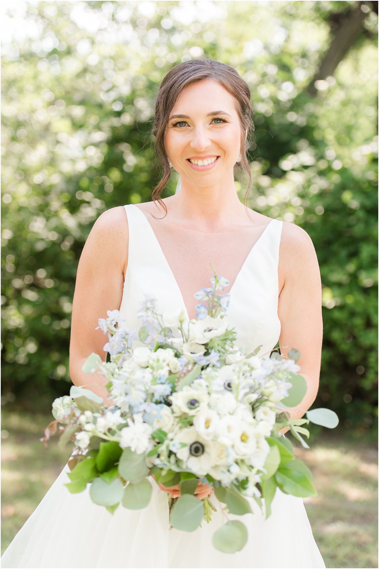 bride stands holding bouquet of white and blue flowers 