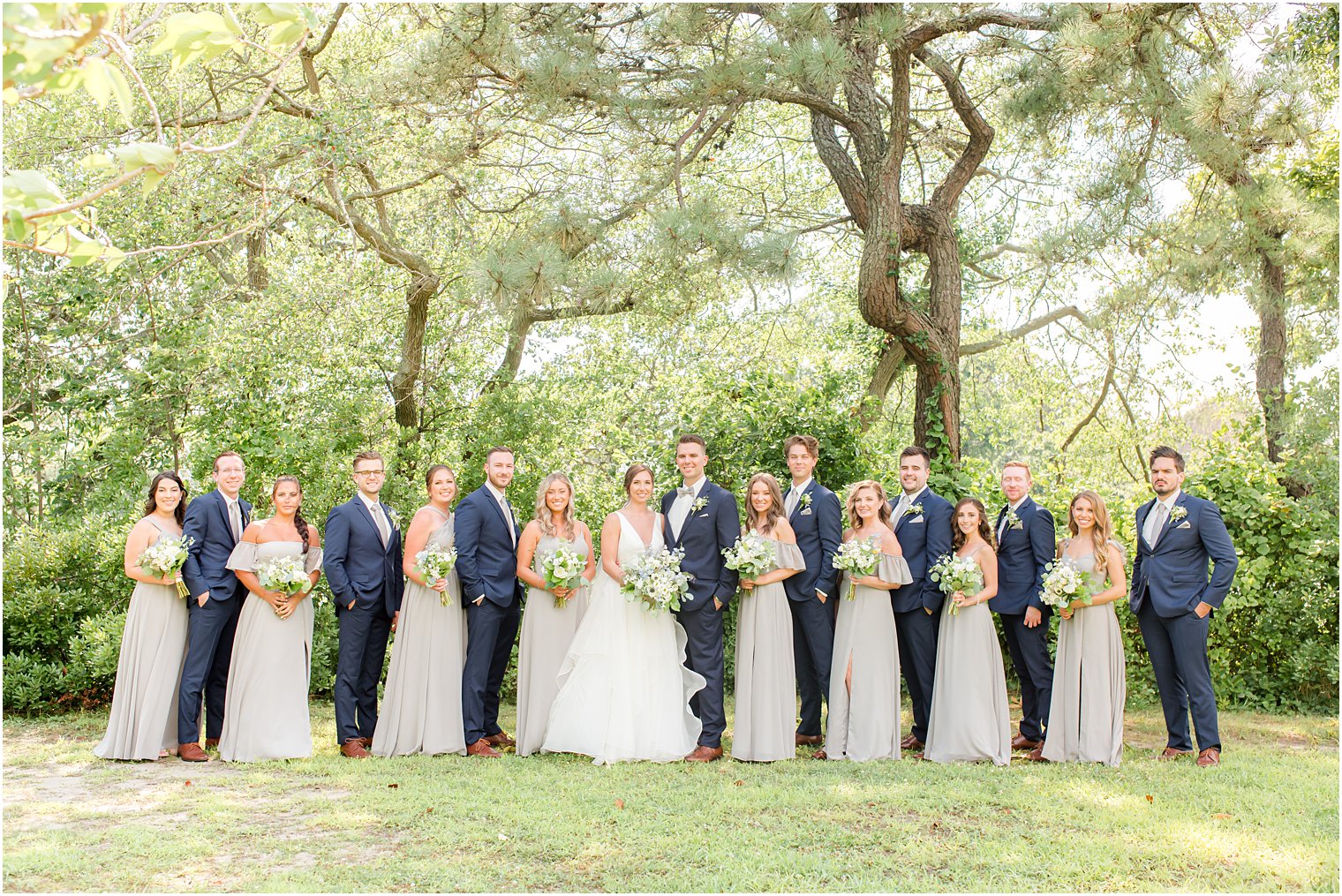 bride and groom stand with wedding party in navy blue and grey