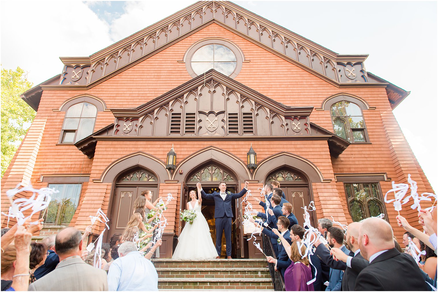 bride and groom cheer as guests wave ribbons on steps at St. Peter's Church