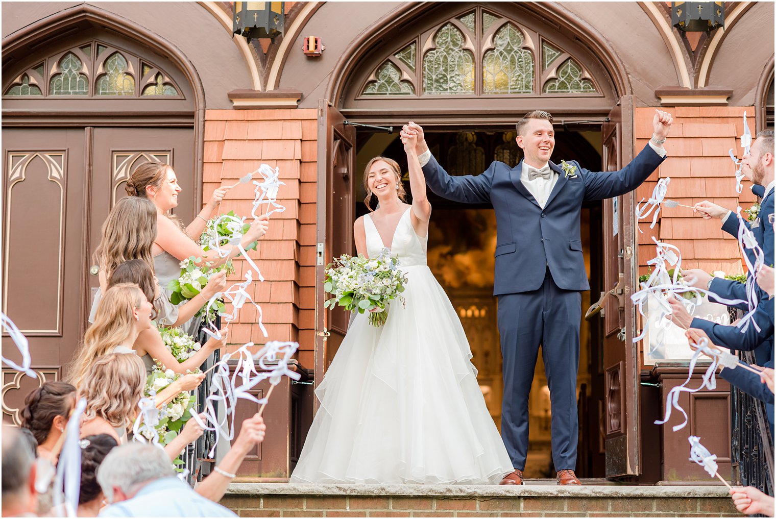 bride and groom cheer as guests wave ribbons on steps at St. Peter's Church