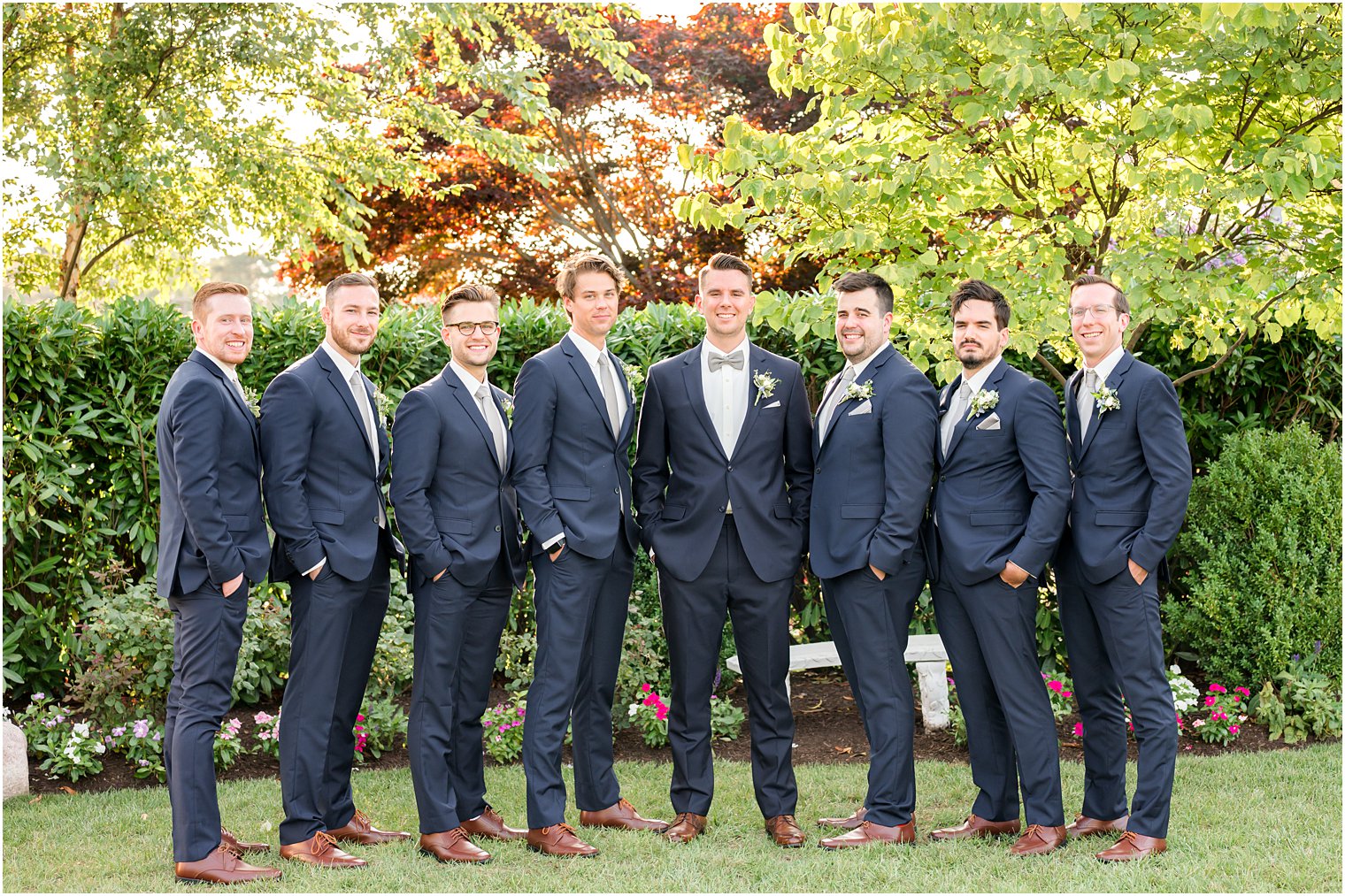 groom stands with groomsmen in navy suits outside Crystal Point Yacht Club