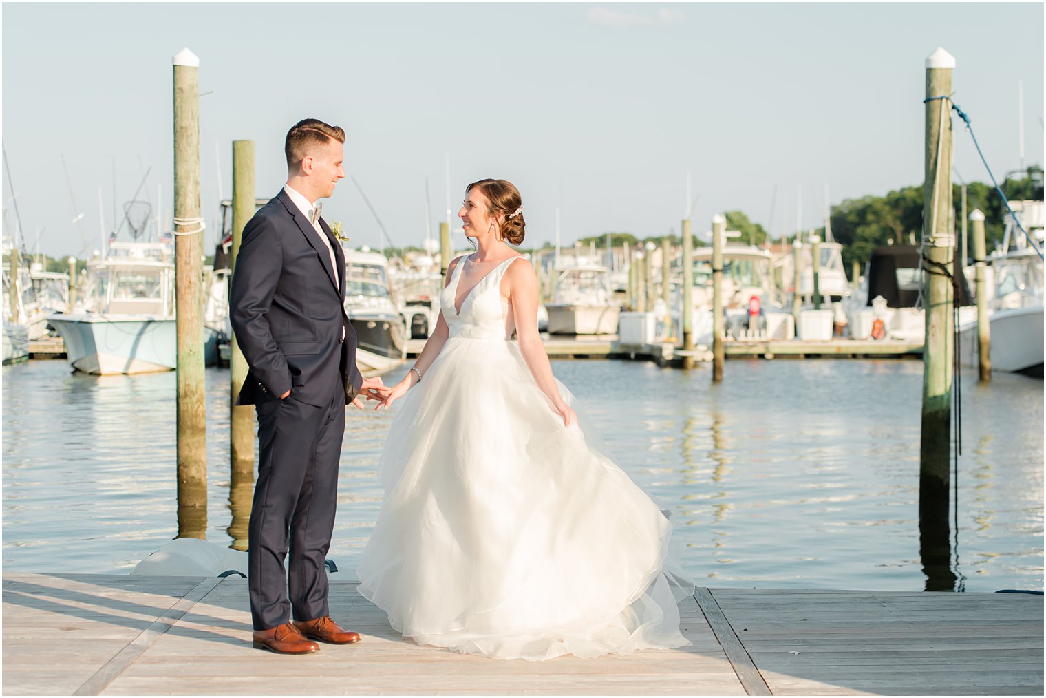 bride and groom talk standing on wooden dock at Crystal Point Yacht Club