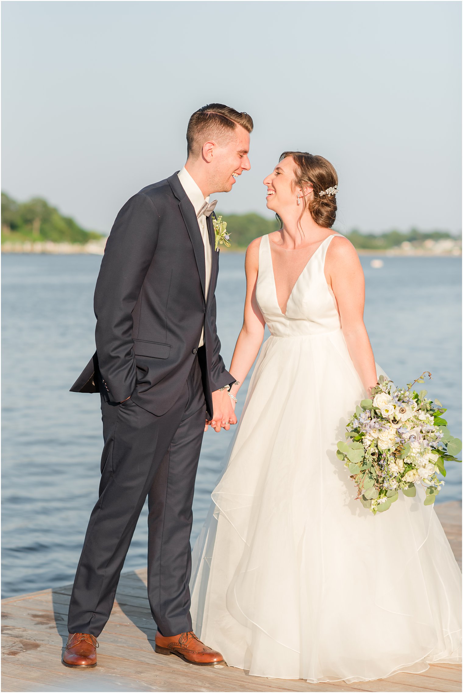 newlyweds laugh leaning together on wooden dock