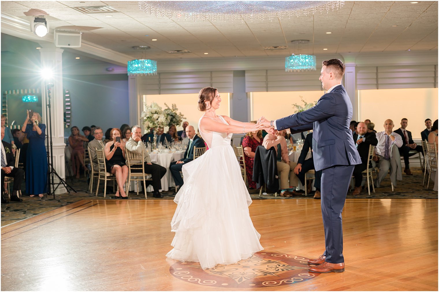groom twirls bride on dance floor during first dance 