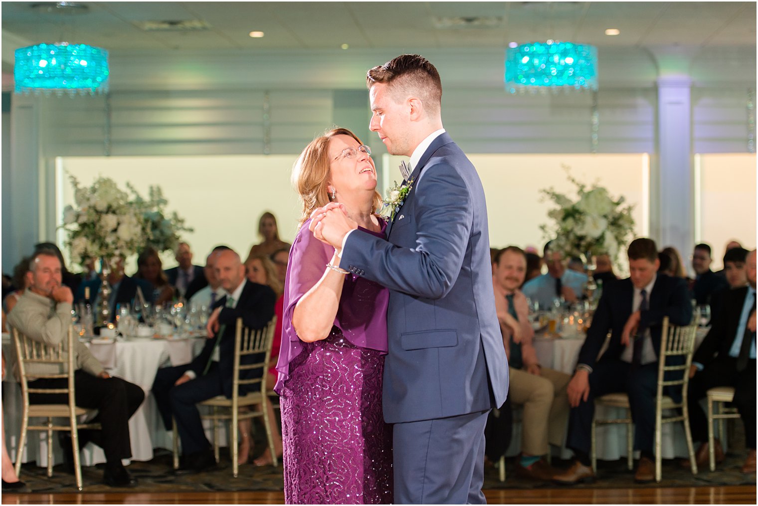 groom dances with mother in purple dress at Crystal Point Yacht Club