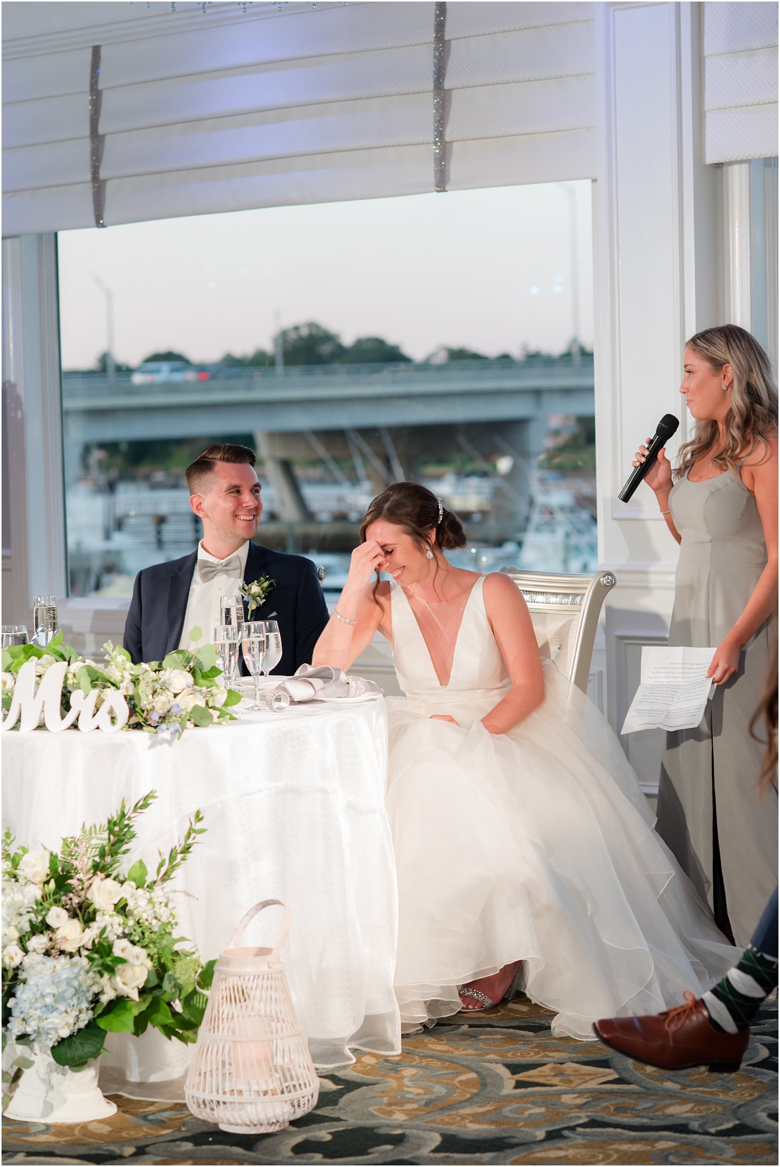 bride covers face during toast from bridesmaid 