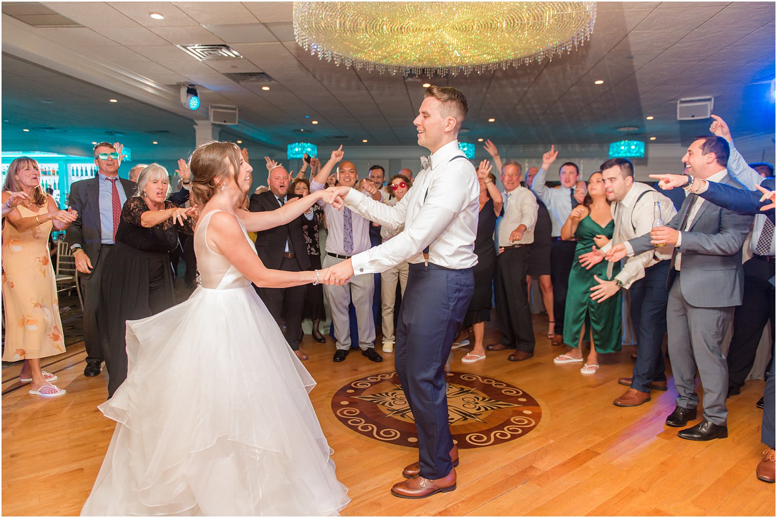 bride and groom dance among guests on dance floor at Crystal Point Yacht Club