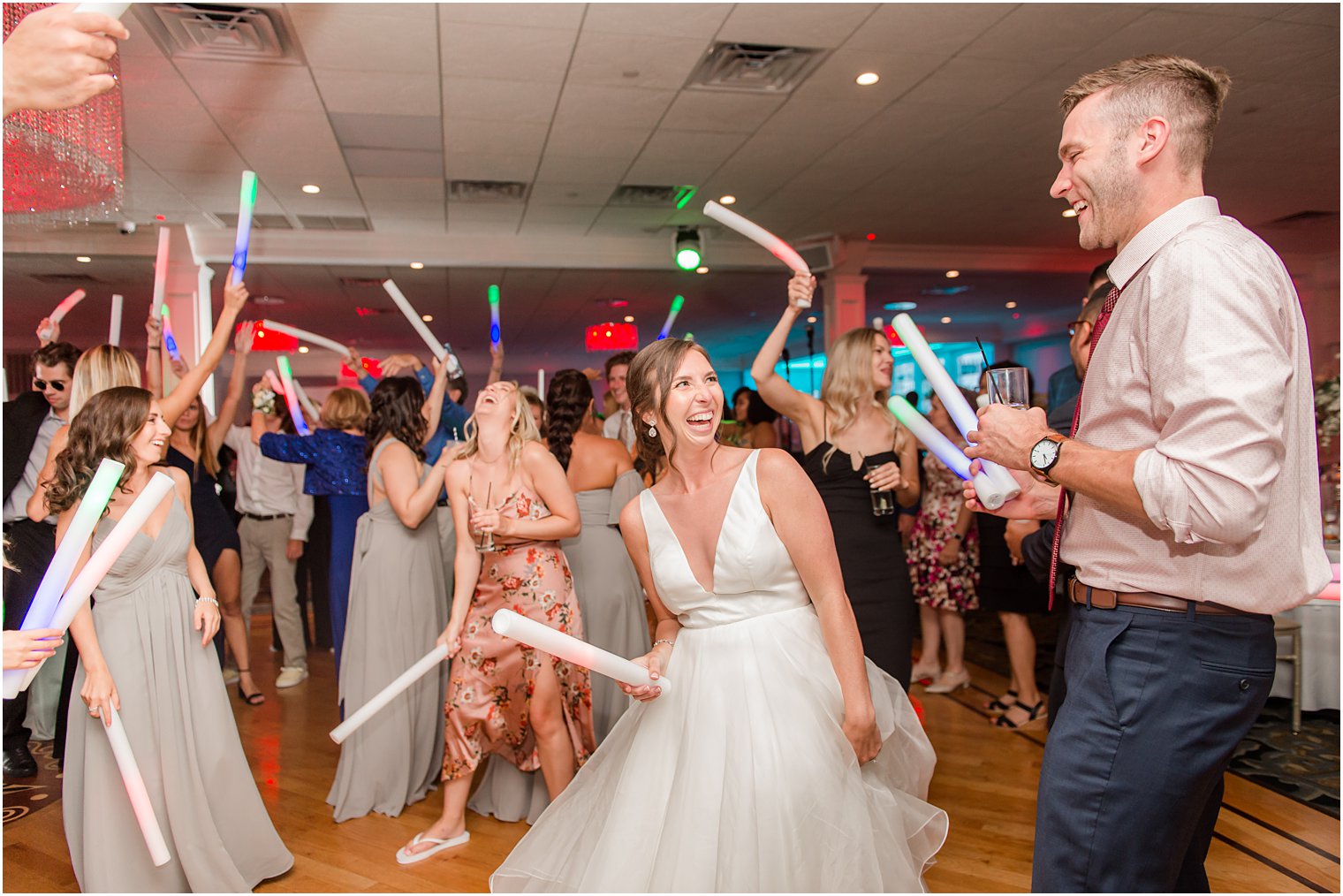 bride smiles and laughs dancing with groom with glow sticks 