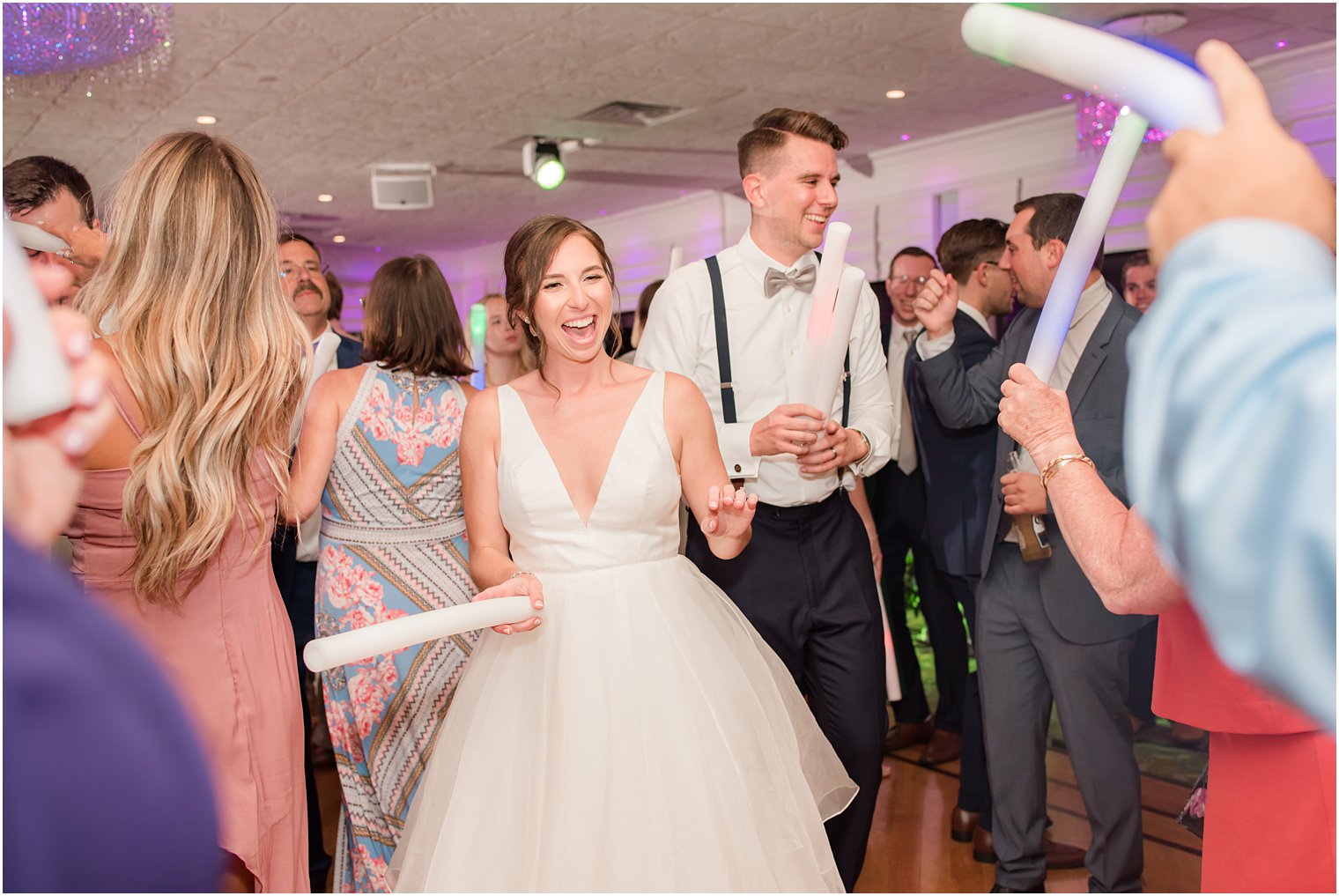 newlyweds dance with guests with glow sticks at Crystal Point Yacht Club