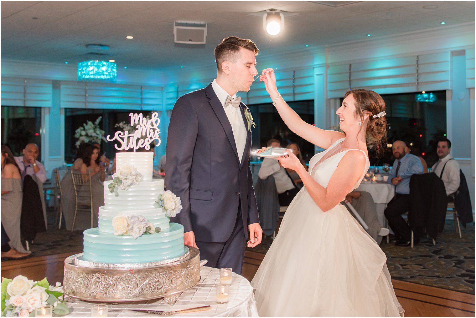 bride feeds groom cake during wedding reception at Crystal Point Yacht Club