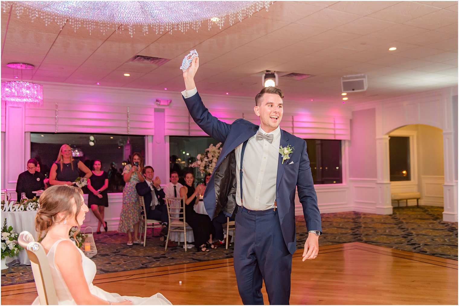 groom holds up garter at Crystal Point Yacht Club
