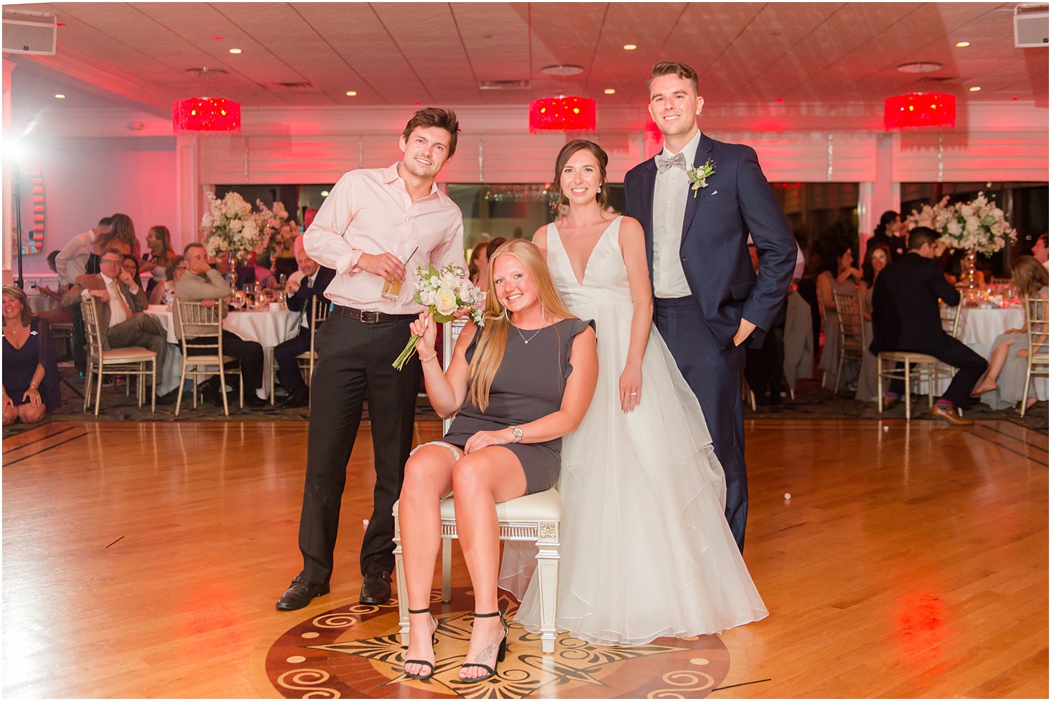 bride and groom pose with winner of bouquet and garter toss