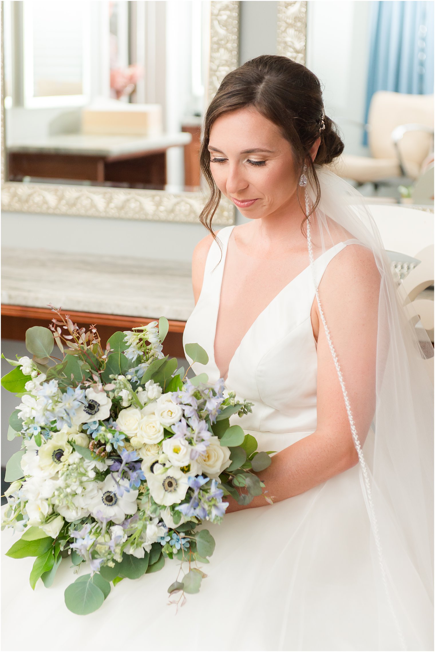 bride looks down at white and blue bouquet for coastal wedding at Crystal Point Yacht Club