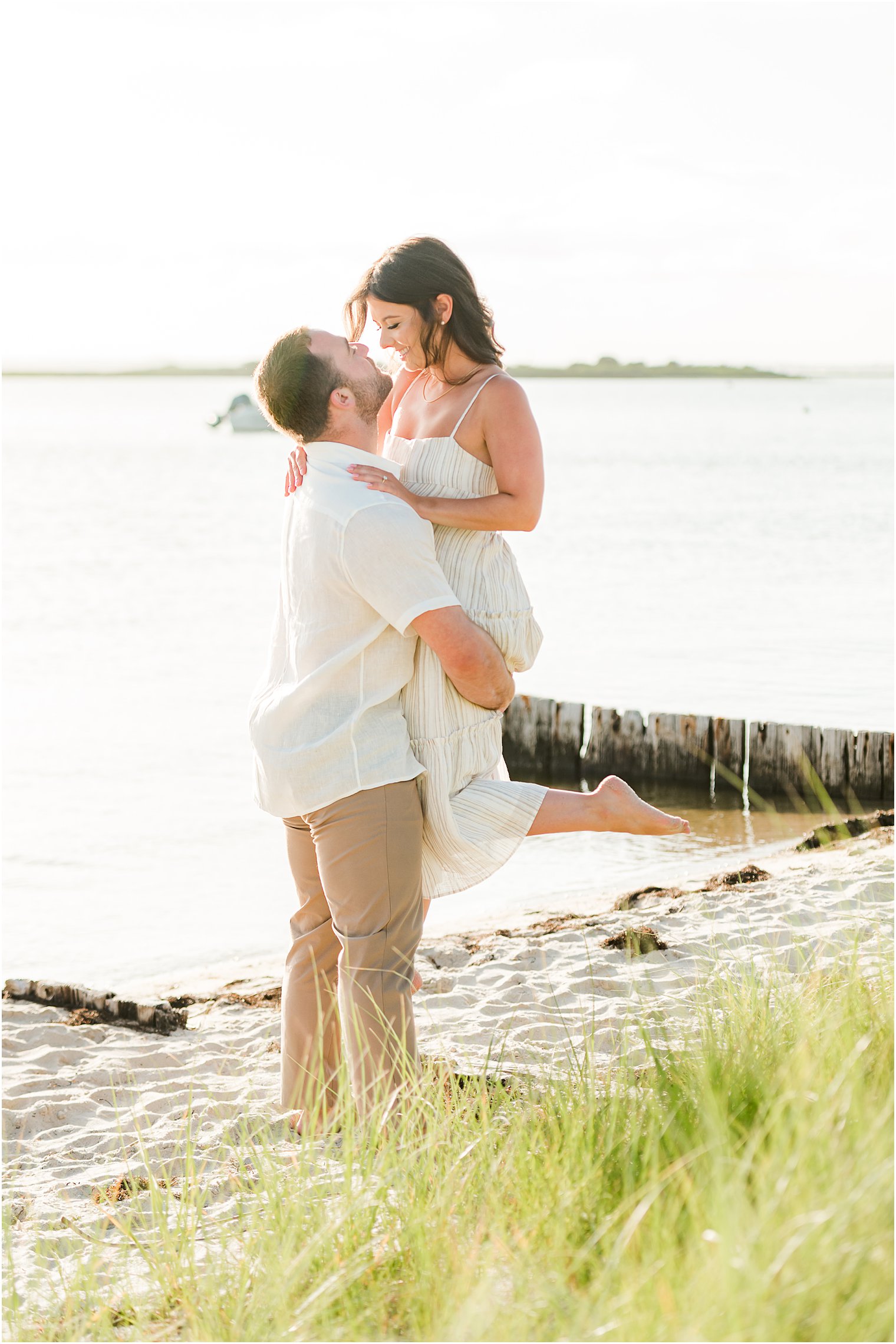groom lifts up bride during beach engagement session in New Jersey 