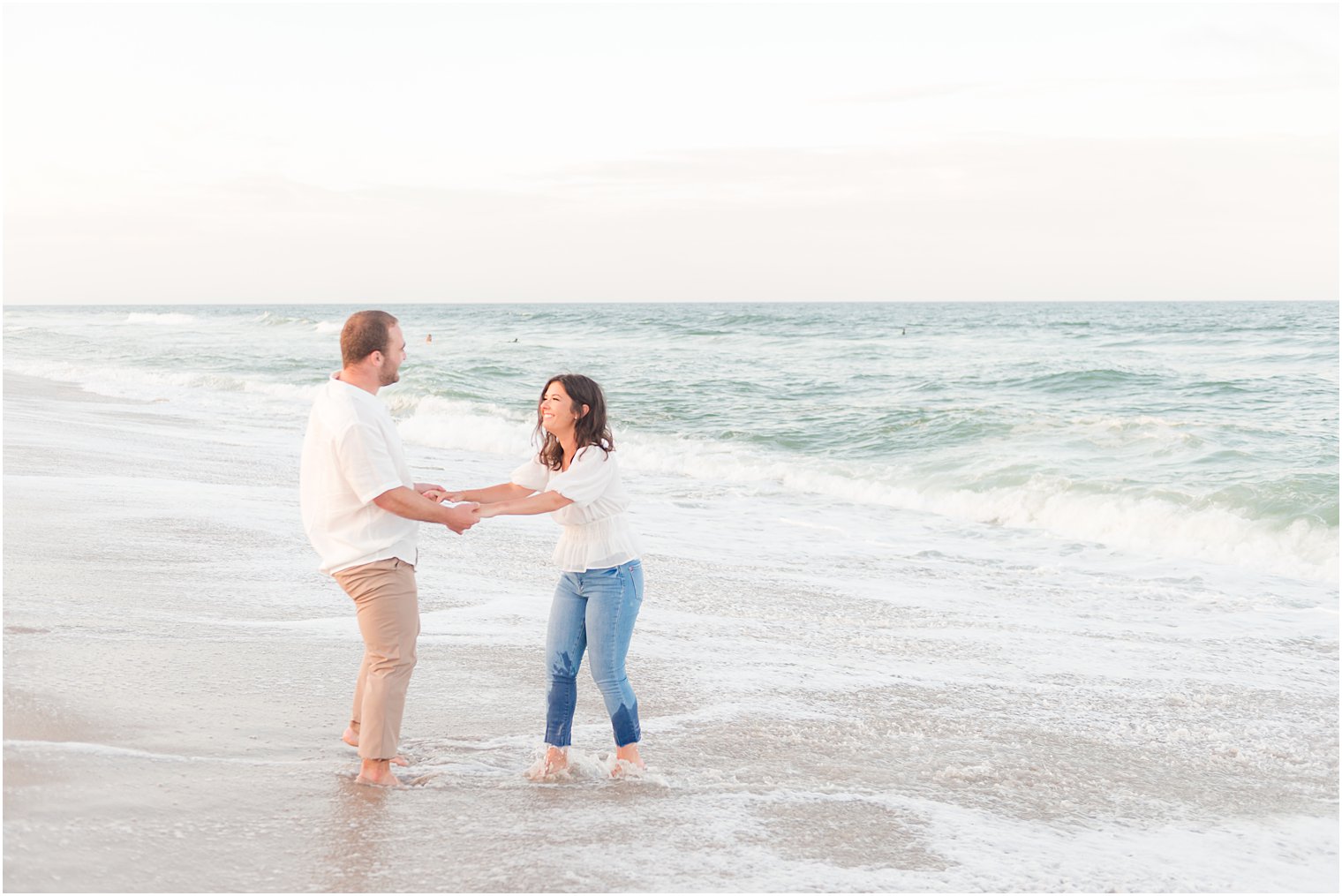 couple plays in water during engagement photos at Lavallette Beach